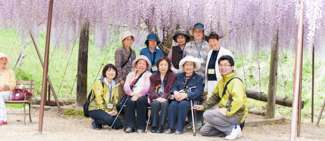 写真：利用者さまとともに藤棚の前で